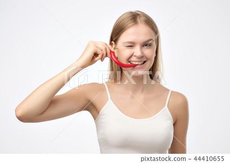 Female mouth holding red hot chili pepper. 44410655