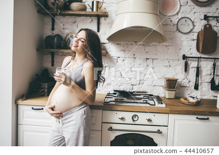 Pretty pregnant woman in kitchen having breakfast and cup of milk 44410657