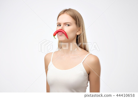 European young woman holding red hot chili pepper like mustache European young woman holding red hot chili pepper like mustache 44410658