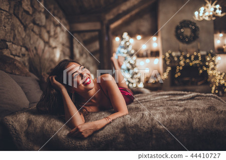 Beautiful asian woman is sitting at home near christmas tree in cozy interior. Interior with 44410727