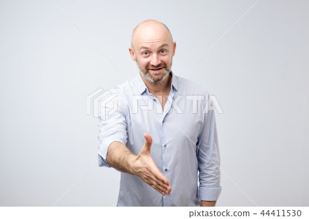 Friendly-looking attractive european man giving a hand in hello gesture while smiling cheerfully 44411530