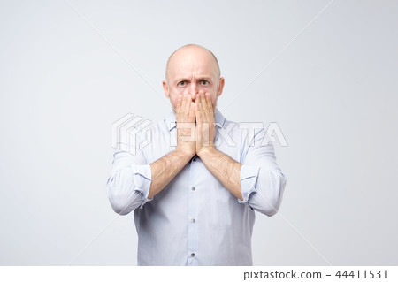 Portrait of a shocked young man covering his mouth with hands 44411531