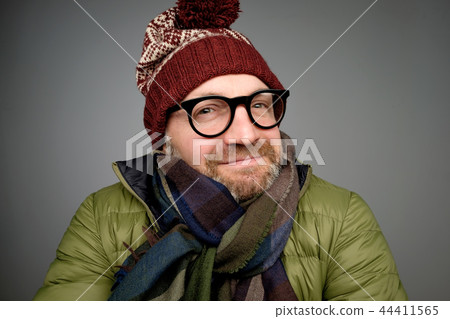 Portrait of a handsome young man smiling wearing warm winter coat, scarf, and funny hat Portrait of a handsome young man smiling wearing warm winter coat, scarf, and funny hat 44411565