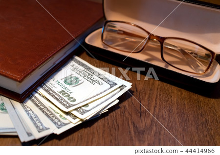 Hundred dollar bills and glasses on a table Hundred dollar bills and glasses on a table 44414966