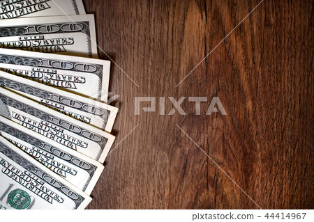 One hundred dollars on a wooden table One hundred dollars on a wooden table 44414967