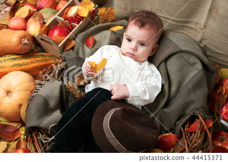 child boy lie on autumn leaves with fruits 44415371