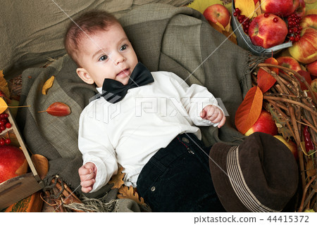 child boy lie on autumn leaves with fruits child boy lie on autumn leaves with fruits 44415372