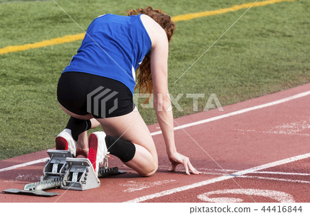 High school female runner in the starting blocks 44416844