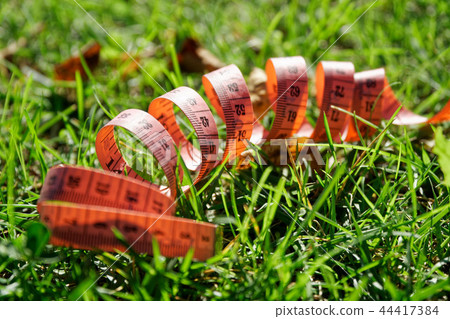Fit centimeter on green grass measuring tape 44417384