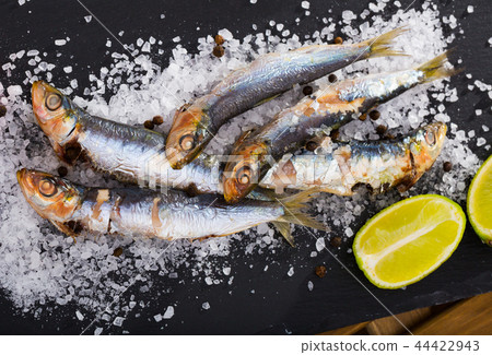 Tasty dish of baked sprat baked in the oven on a pillow of sea salt Tasty dish of baked sprat baked in the oven on a pillow of sea salt 44422943