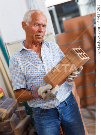 Man inspecting brick for installing wall 44424263