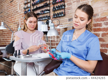 Manicurist showing color samples of nail polish in nail salon Manicurist showing color samples of nail polish in nail salon 44424265