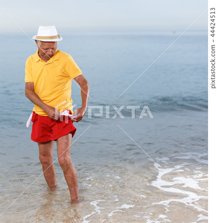 Serious man shows empty pockets near ocean 44424513