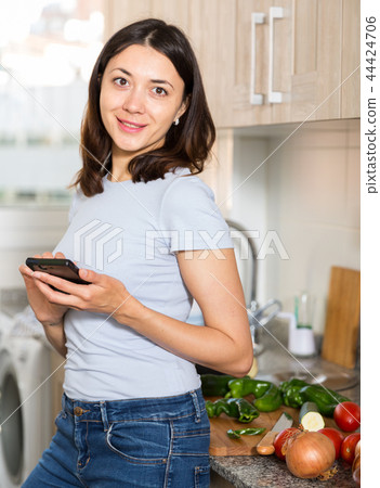 Young girl housewife using phone at home kitchen 44424706