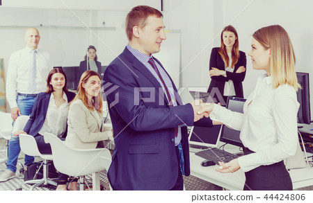 businessman and businesswoman shaking hands in office 44424806