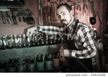 man worker examining colorants for leather in leather workshop 44424886