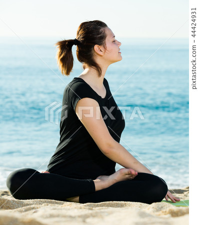 Portrait of sportswoman which is practicing set of stretching exercises in black T-shirt 44424931