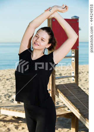 Adult woman in black T-shirt is practicing stretching Adult woman in black T-shirt is practicing stretching 44424958
