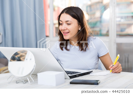 Young woman student working with laptop and pen at table Young woman student working with laptop and pen at table 44425010