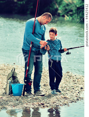 Portrait of father and son fishing with rods 44425412