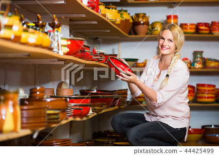 young woman selecting ceramics with red enamel in atelier young woman selecting ceramics with red enamel in atelier 44425499