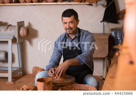 Male working with clay on pottery wheel 44425666