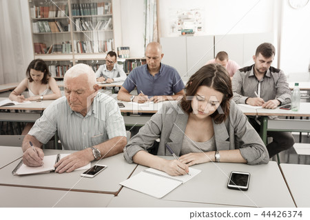 Young girl and mature man take a written exam Young girl and mature man take a written exam 44426374