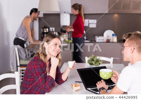 Girl talking to guy in kitchen of hostel Girl talking to guy in kitchen of hostel 44426995