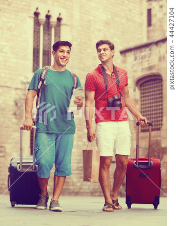 Men tourists are walking with suitcases in unknown city. 44427104