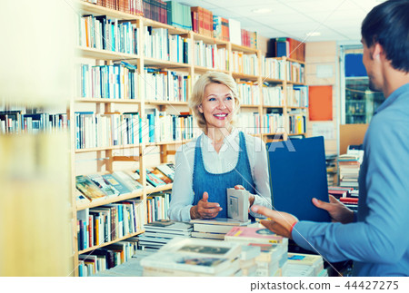 mature woman with assistant in book store. mature woman with assistant in book store. 44427275