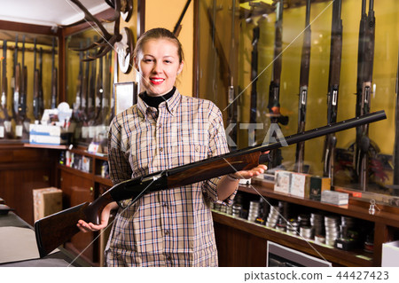Nice female in hunting shop with rifle 44427423