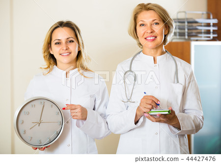 Two female doctors holding clock 44427476