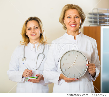 Two female doctors holding clock 44427477