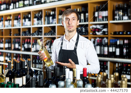 Man seller wearing uniform having bottle of wine 44427570
