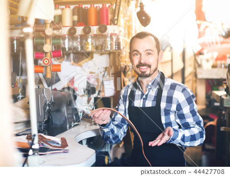 male worker sewing stitches on belt in leather workshop male worker sewing stitches on belt in leather workshop 44427708