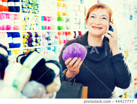Woman with needlework accessories and talking on phone Woman with needlework accessories and talking on phone 44427777