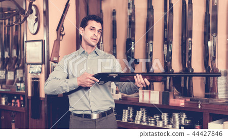 Handsome adult male in hunting shop with rifle in hands Handsome adult male in hunting shop with rifle in hands 44427846