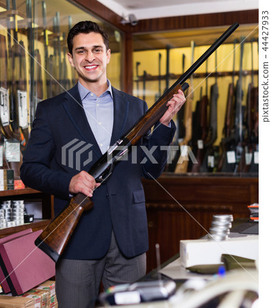 Handsome adult male in hunting shop with rifle in hands Handsome adult male in hunting shop with rifle in hands 44427933
