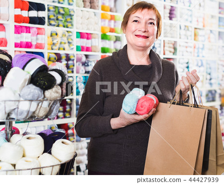 Mature female is standing in needlework store Mature female is standing in needlework store 44427939