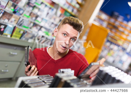 Surprised guy choosing DVD Surprised guy choosing DVD 44427986