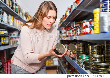 Woman customer holding canned fish goods in the food store 44428065