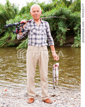 Fisherman posing with catch at riverside Fisherman posing with catch at riverside 44428177