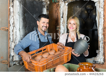 man and woman potters holding ceramic vessels in atelier 44428268