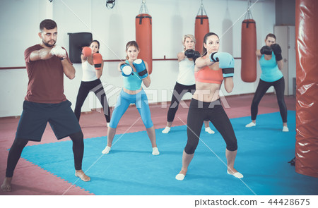 group of females and their trainer are boxing in gym 44428675