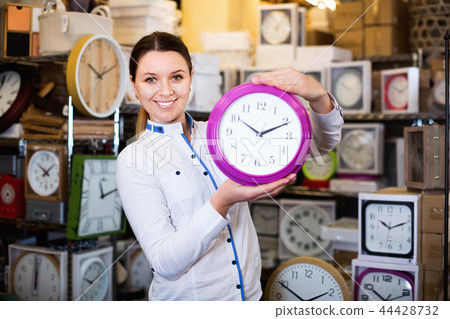 Woman is choosing new clock for her home in the store. Woman is choosing new clock for her home in the store. 44428732