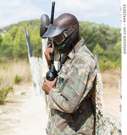 Paintball player in camouflage standing with gun after paintball match Paintball player in camouflage standing with gun after paintball match 44428858