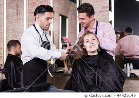 Two hairdressers making hairstyle for female client 44429149