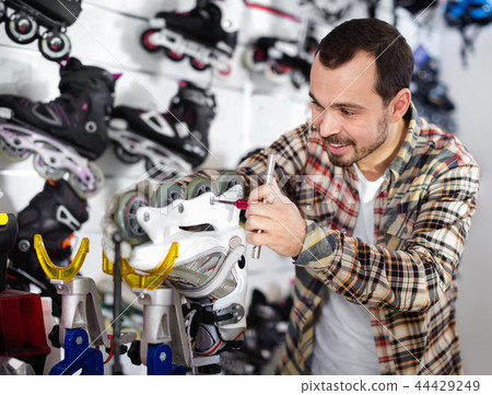 Male repairer fixing roller-skates in sports store Male repairer fixing roller-skates in sports store 44429249