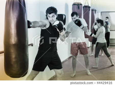 Young athlete is beating a boxing bag Young athlete is beating a boxing bag 44429416
