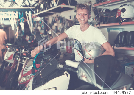 Young motorcyclist holding motorbike with helmet Young motorcyclist holding motorbike with helmet 44429557